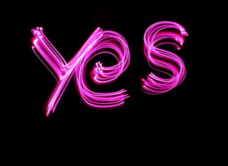 Long exposure photograph of neon colour in an abstract swirl, parallel lines pattern against a black background. Light painting photography.