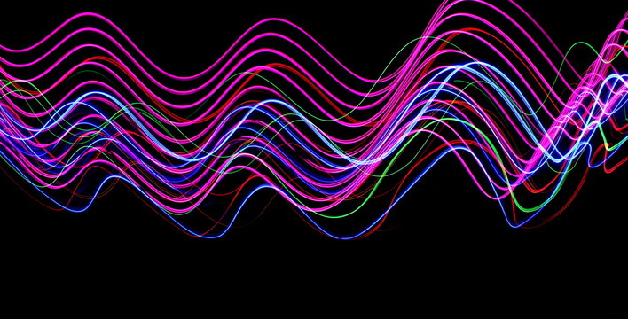 Long exposure photograph of neon colour in an abstract swirl, parallel lines pattern against a black background. Light painting photography.