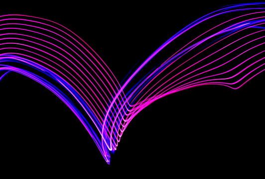 Long exposure photograph of neon pink and purple colour in an abstract swirl, parallel lines pattern against a black background. Light painting photography.