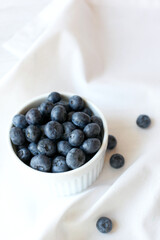 Photo of blueberries in a white bowl on a white tablecloth