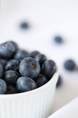 Photo of blueberries in a white bowl on a white tablecloth