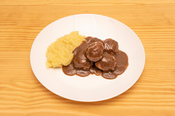 Delicious beef meatballs in sauce with homemade mashed potatoes on white plate in Spanish tapas restaurant