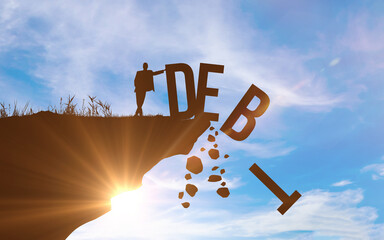 DEBT concept. Silhouette of man pushed off DEBT word from a cliff. Blue sky background. Success and profit concept photo