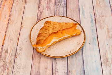 butter croissant filled with smoked Norwegian salmon and cream cheese on a porcelain plate