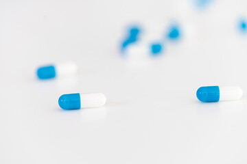 white and blue pharmaceutical medicine capsules on a white background.