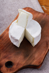 Camembert cheese on a wooden cutting board. White cheese on a wooden background. Copy space