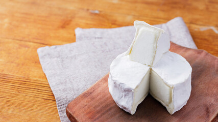 Camembert cheese on a wooden cutting board. White cheese on a wooden background. Copy space