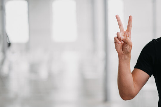 Selective Focus Shot Of A Person Holding Up Two Fingers In A Peace Sign