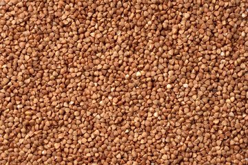 Uncooked buckwheat texture. Brown grains for breakfast background. Traditional Russian food backdrop. A high-quality photo of dry croup