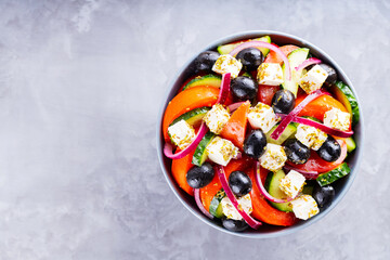 Greek salad with feta and olives on a gray background. Healthy mediterranean salad. Copy space. Top view