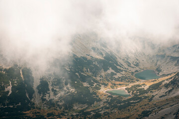 Fototapeta premium Stunning view from Musala summit at Rila glacier lakes on a misty, foggy, moody day and a sift light