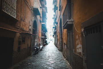 Fototapeta na wymiar Scenic view of typical narrow alleyway lined with scooters and laundry lines in the Medieval Centro Storico of Naples, Italy