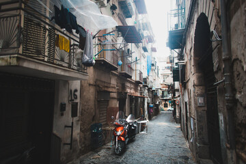 Scenic view of typical narrow alleyway lined with scooters and laundry lines in the Medieval Centro...