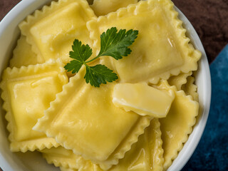 Italian appetizing ravioli in a bowl. A piece of butter is melted on top. Garnish with a green mint leaf. Macro photography. Italian cuisine. Restaurant, hotel, cafe, food design, culinary blog.