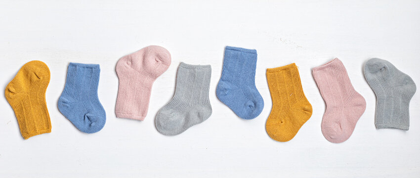 Collection of cute colore baby socks for little feet. Warm socks for cold weather of fall and winter season. Top view, flat lay background. Banner