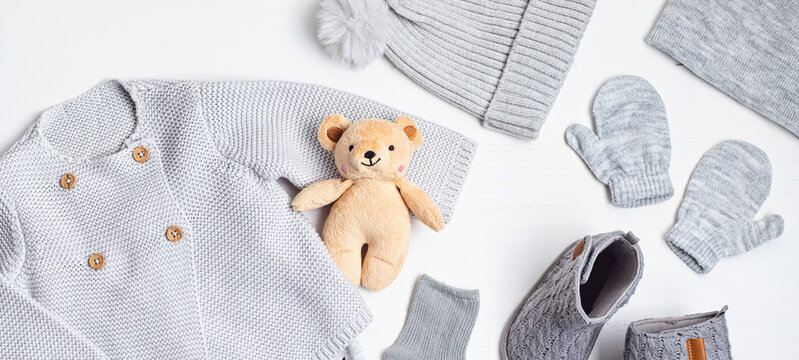Collection of cute organic  baby clothes and booties. Warm outfit for cold weather of fall and winter season in gray colors. Newborn gifts, baby shower, second hand clothes, donation idea. Banner