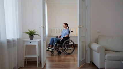 A young disabled woman is riding in her wheelchair around the room