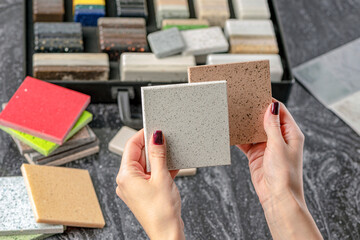 Choice of tiles. Female hands hold samples of tiles of different colors. Woman in store chooses...