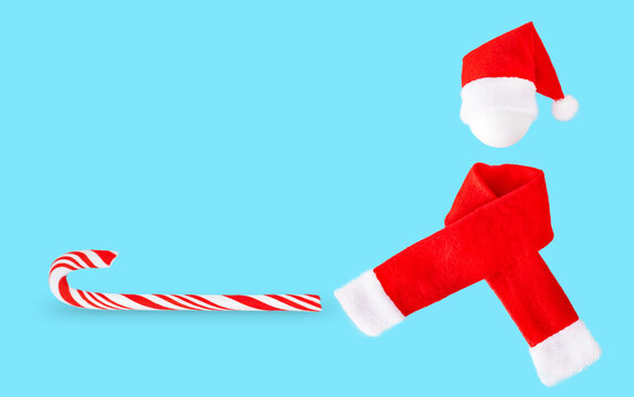 Christmas background with red hat, scarf and lollipop on blue background