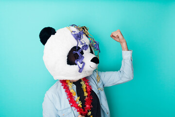 Excited man in panda mask with party ornaments celebrating on colored background