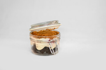 Opened transparent isolated jar with sweet delicious dessert inside divided in layers on white background