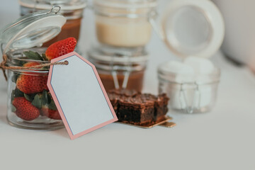 Opened transparent isolated jars with price tag and strawberry on table with sweet delicious dessert inside on white background