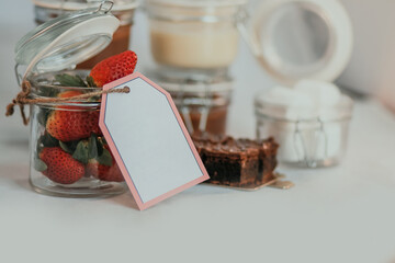 Opened transparent isolated jars with price tag and strawberry on table with sweet delicious dessert inside on white background
