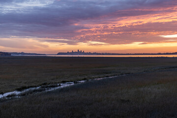 Sunset over grass with river water city