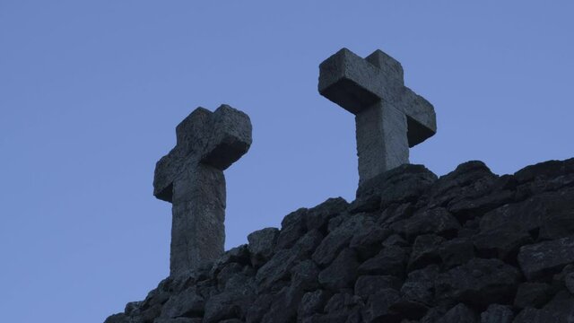 Three stone crosses backlit. Three crosses in Parc Guell. Graveyard cross. Church. Blue hour photo.