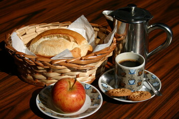 Traditiona breakfast. French bread, cup of black coffee, cookies and apple on the rustic table.