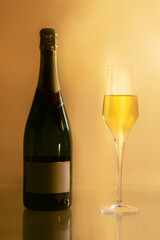 A champagne bottle with empy label with a champagne glass on a yellow background