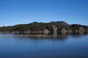 The lake in a sunny morning. Panorama view of the forest, lake and the perfect reflection of the sky in the blue water. 