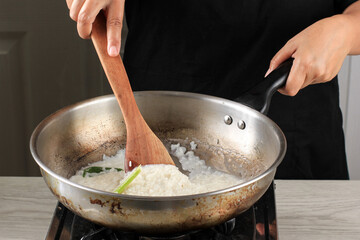 Asian Women Boiled Sticky Rice on A Pan in the Kitchen. Stir Sticky Rice with Wooden Spatula