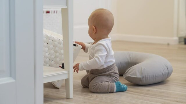 Baby exploring all around the house, 7 month old baby boy crawling sitting on the floor, cute child playing at home touching everything. High quality 4k footage