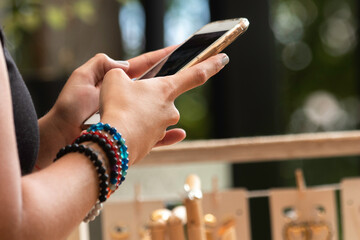 Woman hands with mobile phone with colored bracelets