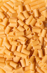 vertical view over yellow uncooked rigatoni round ridged pasta