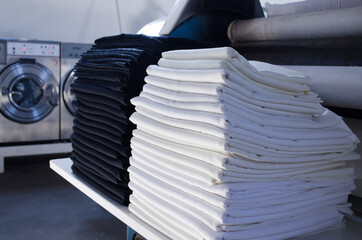 Stack of folded black and white cloths in an industrial laundry.