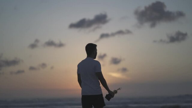 Silhouette of a proud man lifting a trophy on the beach at sunset - Winner Achievement in Slow Motion