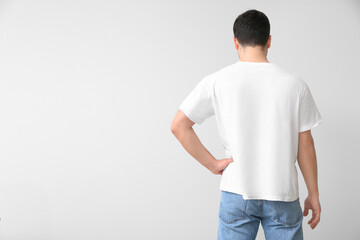 Handsome young man in stylish t-shirt on light background, back view