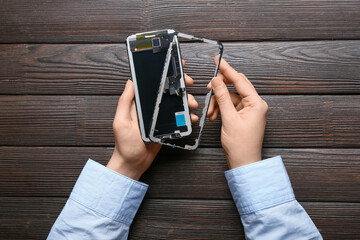 Woman holding disassembled mobile phone on wooden background