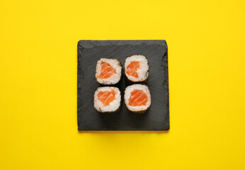 Delicious salmon maki rolls on color background