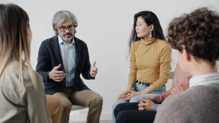 Therapist is speaking to patients during group session holding hands giving help and support while people with closed eyes are listening