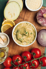 Bowl with tasty baba ghanoush and vegetables on table