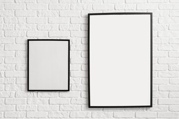 Blank poster frames hanging on brick wall