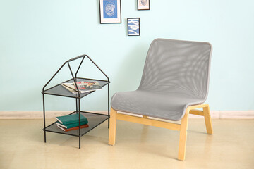 Stylish shelves with armchair near color light wall