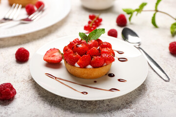 Plate with tasty berry tart on grunge background