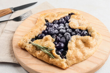 Board with tasty blueberry galette on light background, closeup