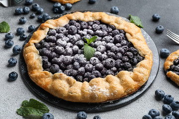 Plate with tasty blueberry galette on dark background