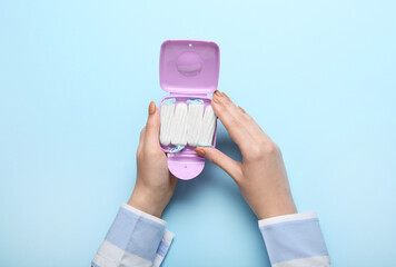 Tampons storage box in female hands on blue background