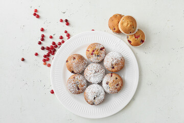 Plate with delicious cranberry muffins on white background